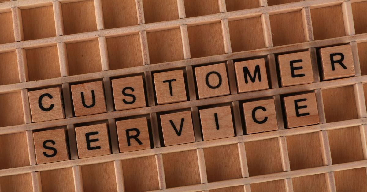 Wooden blocks forming the phrase 'Customer Service' placed inside a wooden grid, symbolizing support and assistance.